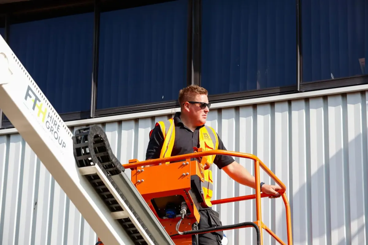 A Cornerstone Pest Control technician on a boom lift alongside a large commercial industrial unit