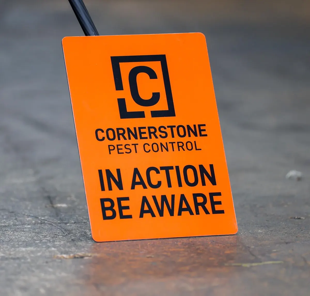An orange Cornerstone Pest Control in action be aware warning board set out on a work site